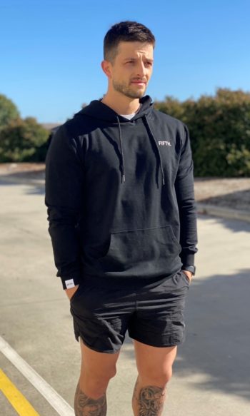 A man standing in the road wearing a black Classic Hoodie Unisex